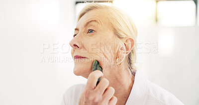 Buy stock photo Woman, gua sha and skincare routine in bathroom with tools, circulation or benefits in house. Mature person, anti aging and stone for wrinkles with blood flow, massage and dermatology at apartment