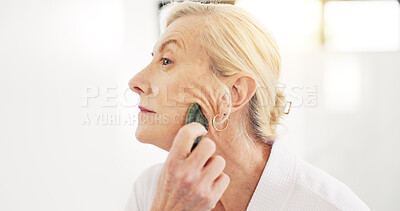 Buy stock photo Woman, gua sha and skincare treatment in bathroom with tools, circulation or benefits in house. Mature person, anti aging and stone for wrinkles with blood flow, massage and dermatology at apartment