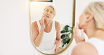 Mature woman, skincare and bathroom mirror for wrinkles, results or inspection for beauty in home. Person, check face and morning routine for anti aging, dermatology or flare with reflection in house