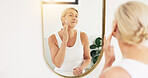 Mature woman, skincare and cream in bathroom mirror for hydration, moisturizer or smile for beauty in home. Person, reflection and routine for anti aging, dermatology and flare with lotion in house