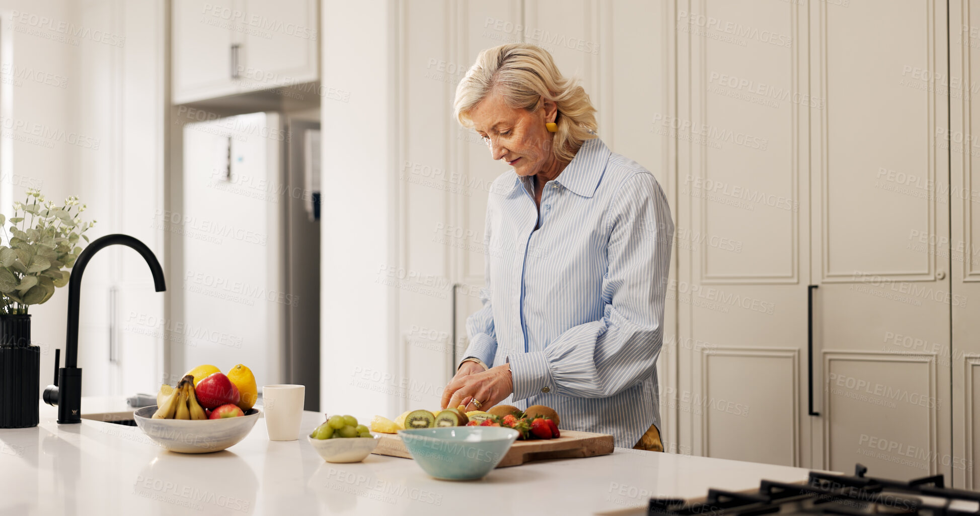 Buy stock photo Senior woman, fruit salad and nutrition in kitchen, recipe and meal prep with organic ingredients at home. Mature person, bowl and process with kiwi, diet and wellness for retirement at apartment