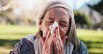 Sick, old woman and blowing nose in park with tissue for influenza, hayfever and sinus infection. Elderly person outdoor, allergies and health problem with toilet paper, illness and virus symptoms.