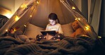 Night, child and reading in fort with tablet, fairy lights or ebook for fantasy bedtime story. Late, girl or relax with digital tech in home for online fairytale, kids storytelling app or literature.
