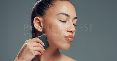Buy stock photo Woman, gua sha or massage in studio with skincare for beauty, dermatology or facial tension. Relax, female person or cosmetic tool for lymphatic drainage, wellness or mockup space on gray background.