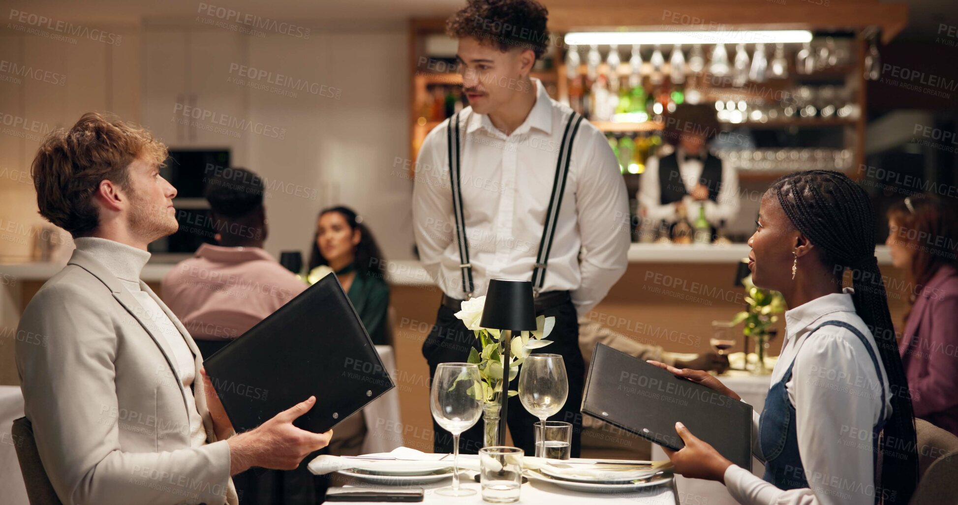 Buy stock photo Waiter, couple and talk at restaurant with menu, decision and discussion for wine list, food or order. People, server and customer experience with service, question and opinion for choice at dinner