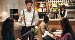Waiter, friends and order at restaurant with menu, decision and discussion for wine list, food or service. Women, man and customer experience with talk, explain and questions for choice at dinner