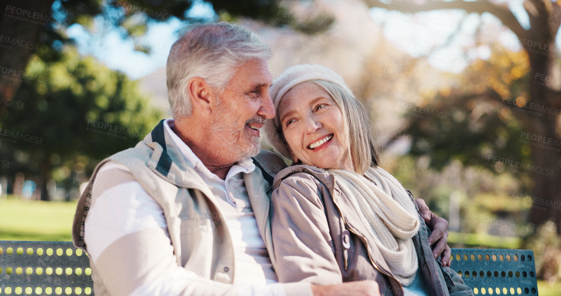 Buy stock photo Retirement, bench and couple in park with hug, love and connection in healthy marriage. Romance, senior man and woman on outdoor seat with embrace, conversation and soulmate in happy relationship.