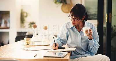 Buy stock photo Woman, writing and notebook with coffee in home for planning, finance reminder and payment timeline. Mature person, beverage and notes for household budget, tracking expenses and financial management