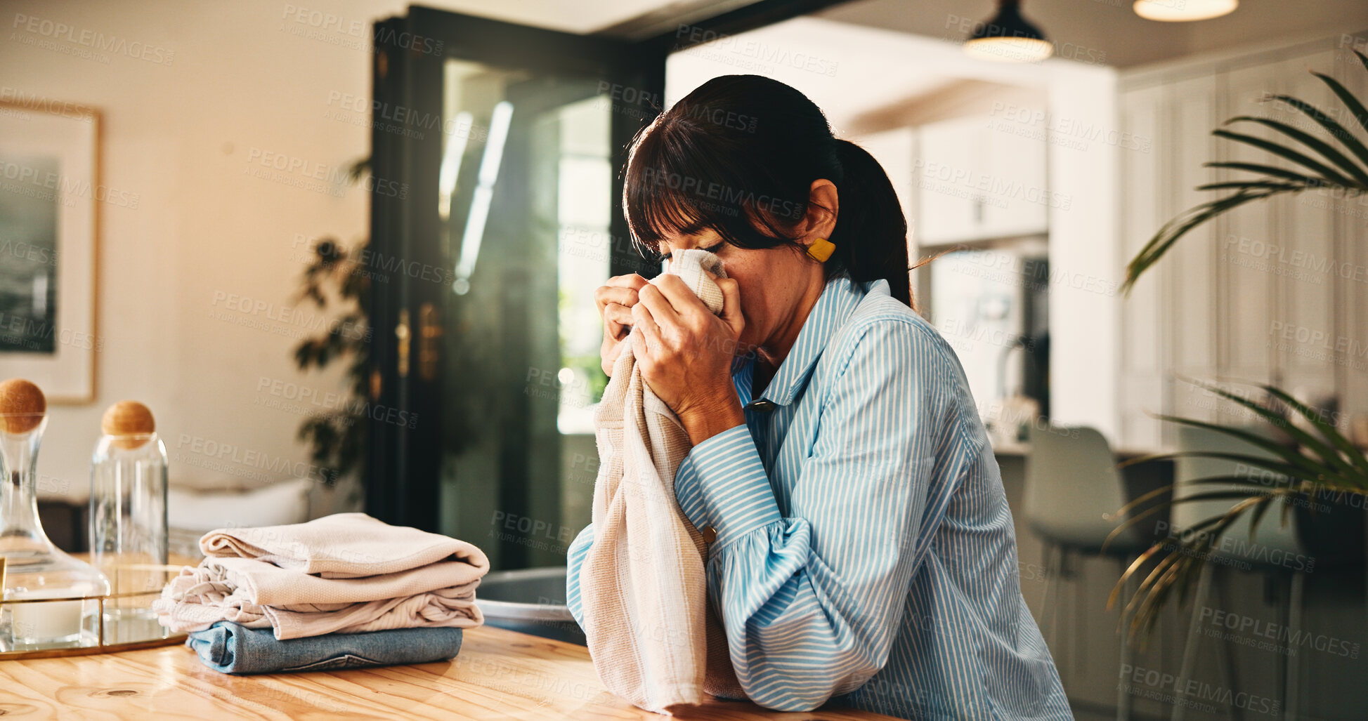 Buy stock photo Woman, smell laundry and fold in home with hygiene, scent and organize with chores for routine. Mature person, clothes and fabric with fragrance, cleaning and packing with sanitation at apartment