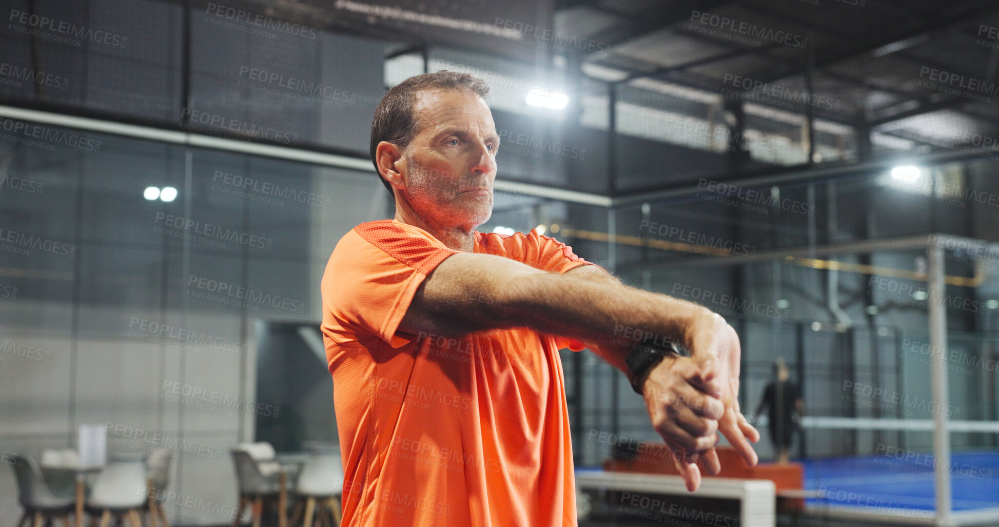 Buy stock photo Fitness, padel and mature man stretching on court for match preparation, start practice and workout. Exercise, person and serious with arm warm up at indoor tennis club for sport performance and game