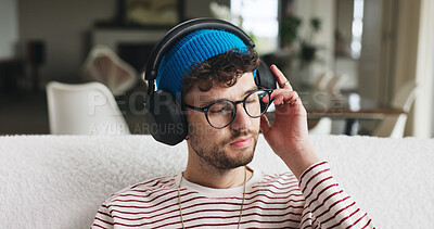 Buy stock photo Headphones, listen and man on sofa in home with music, playlist or radio on weekend. Thinking, audio technology and male person streaming album, podcast or song online in living room at apartment