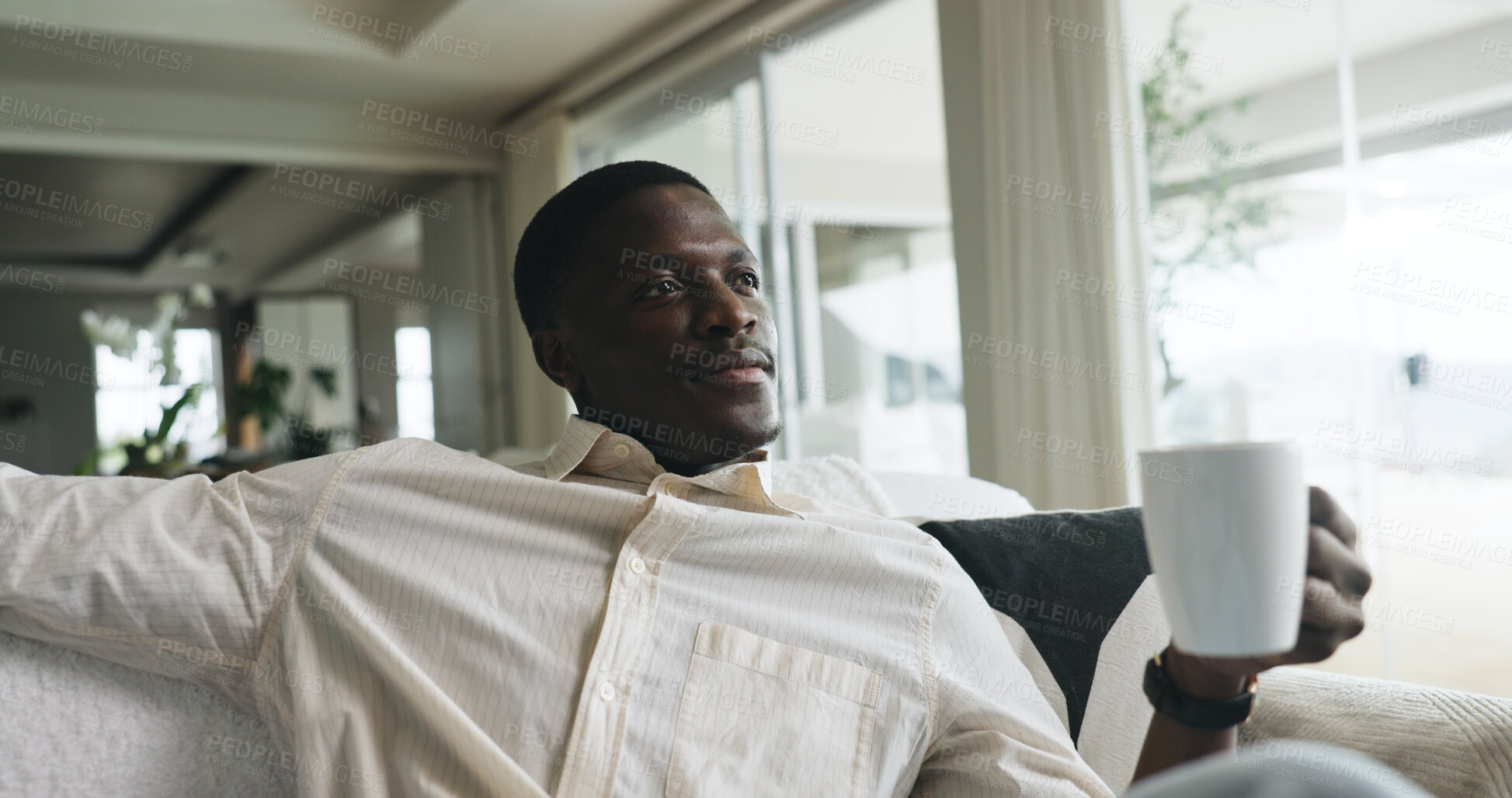 Buy stock photo Morning, thinking and black man on sofa with coffee, calm and reflection on weekend break. Smile, thoughts and male person in house with warm beverage, mindfulness and gratitude in Sunday routine.