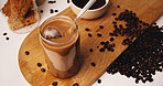 Ice, coffee and straw with glass on table in kitchen of home for caffeine beverage, breakfast and morning brew. Cappuccino, cold latte drink and prepare with above of cup for liquid and beans
