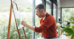 Mature man, painting and canvas with frame for art, drawing or creative sketching in home. Male person, artistic or landscape painter with brush or color for natural scenery, skill or talent in house