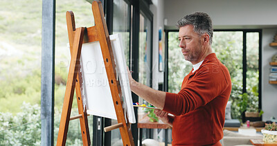 Buy stock photo Mature man, painting and canvas with easel for art, drawing or creative sketching in home. Male person, artistic or painter with brush or color palette for artwork, creativity or talent in house
