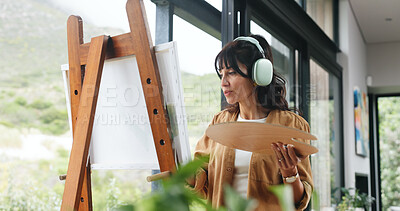 Buy stock photo Painting, artist or headphone by window for creativity project, self expression or concentration for craft. Tech, streaming music or mature woman with artistic activity, creation or low angle in home