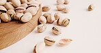 Space, nuts and pistachios on table for diet, vegan meal and healthy snack for nutrition. White background, production and roasted seeds on wooden board for organic food, natural vitamins and protein