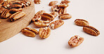 Space, nuts and pecan on table for diet, vegan meal and healthy snack for nutrition. White background, production and roasted seeds on wooden board for organic food, natural vitamins and protein
