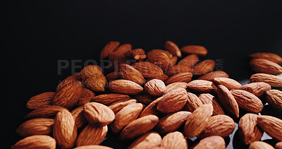 Buy stock photo Black background, nuts and almonds in studio for diet, vegan meal and healthy snack for nutrition. Space, food production and harvest of roasted seeds for organic supplements, natural fats or protein