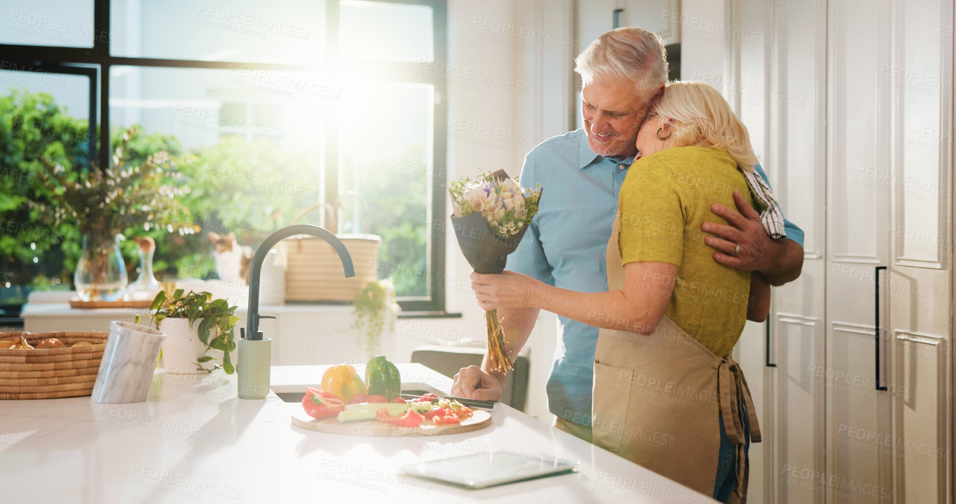 Buy stock photo Hug, flowers and cooking with old couple in kitchen of home for anniversary celebration, romance and gift. Love, present and bouquet with senior man and woman in house for date and meal prep