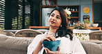 Eating, relax and thinking with woman on sofa in living room of home for hunger or nutrition. Bowl, snack and vision with happy Indian person chilling in apartment for break, diet or weekend me time