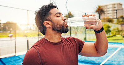 Buy stock photo Man, drinking water and break at tennis court, sports and hydration for wellness with exercise routine. Person, athlete and bottle for electrolytes, training or fitness with rest for game in city