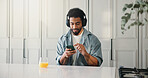Man, relax and headphones with phone at house for social media, listening to music and subscription. Male person, orange juice and mobile for streaming podcast, download playlist and entertainment