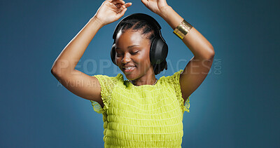 Buy stock photo Headphones, dancing and black woman in studio with music, radio or song for rhythm and energy. Happy, audio tech and African person listening to album for groove entertainment by blue background.