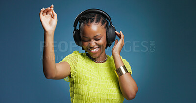 Buy stock photo Headphones, happy and black woman in studio with music, radio or song for rhythm and energy. Dancing, audio tech and African person listening to album for groove entertainment by blue background.