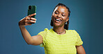Content creation, selfie and social media with black woman in studio for post or profile picture. App, photograph and status update with happy African influencer on blue background for streaming
