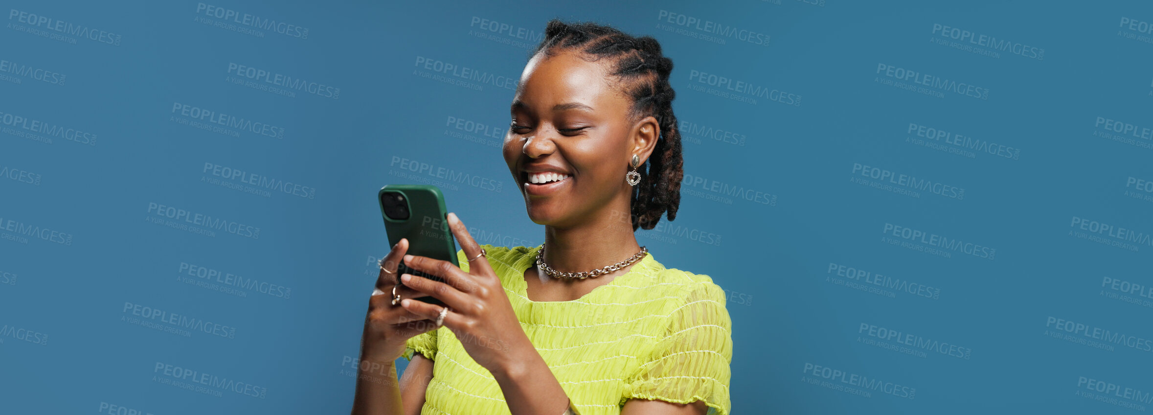 Buy stock photo Funny, cellphone and black woman in studio, typing and communication on blue background. Mockup space, online humor and African person with smartphone, joke and message to contact, app and laughing