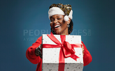 Buy stock photo Christmas, gift box and portrait with African woman on studio space for celebration or surprise. Festive, giving and present with excited black person isolated on blue background mockup for tradition