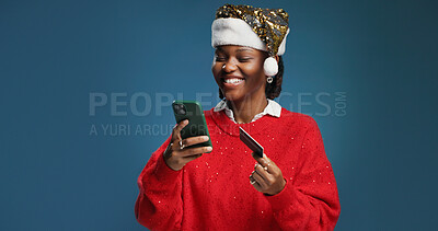 Buy stock photo Happy, black woman and credit card with phone for christmas shopping on a blue studio background. Female person, online shopper or mobile smartphone for app, festive purchase or ecommerce on space