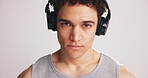 Portrait, athlete and man with headphones in studio for fitness, listening to music and podcast. Male person, streaming song and playlist audio for exercise, training motivation and white background
