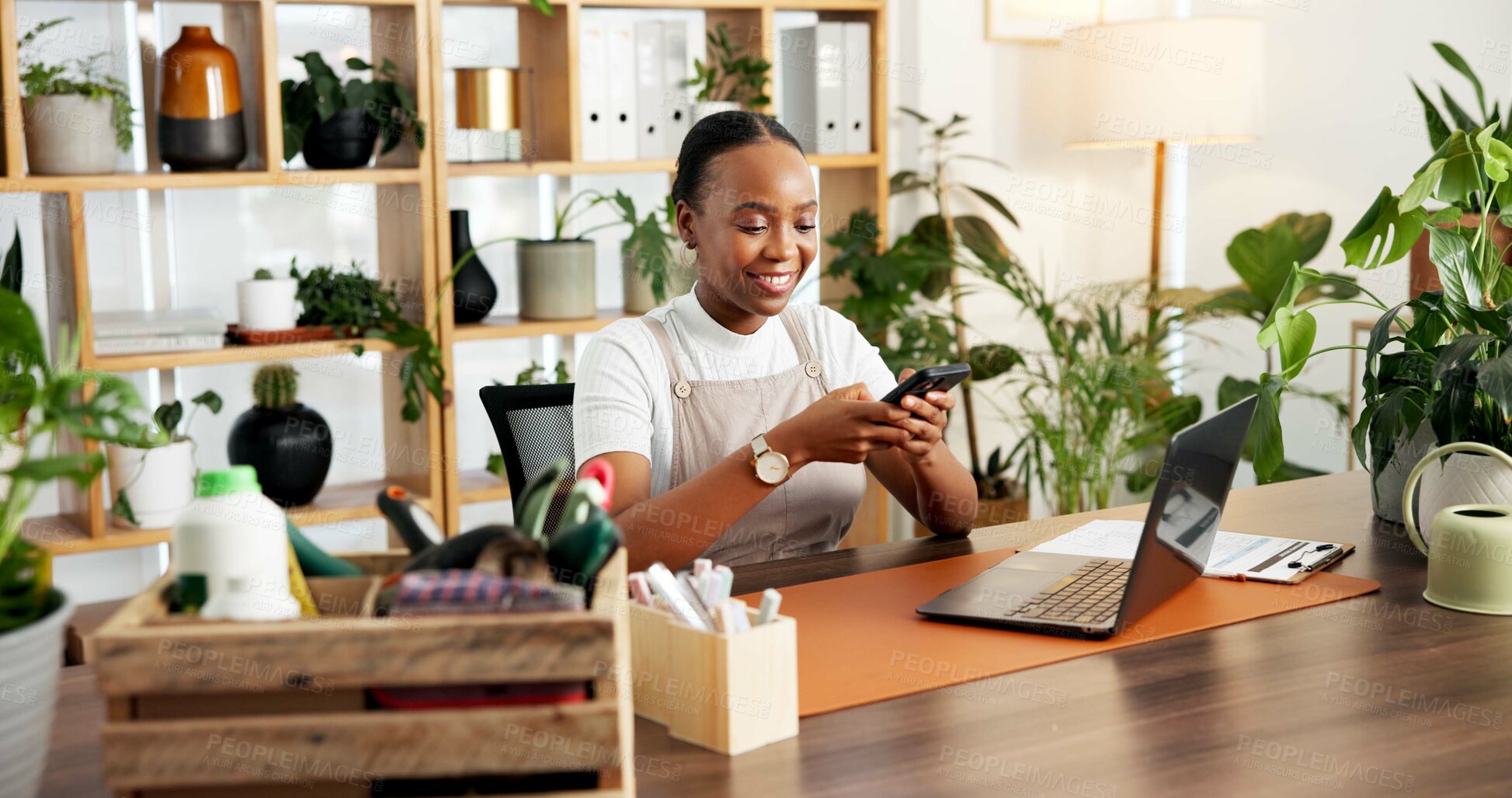 Buy stock photo Phone, plants and typing with black woman in office of nursery for retail or small business sales. App, smile and text message with happy African florist at desk in workplace for communication