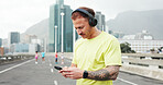 Headphones, fitness and man in city for exercise, marathon training and workout outdoor. Sports, phone and person listening to music, audio and podcast for wellness, health and running in urban town
