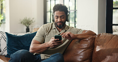 Buy stock photo Headphones, phone and man on sofa in home listening to music, playlist or radio in living room. Happy, audio tech and male person streaming song, album or podcast on mobile app on weekend in house.