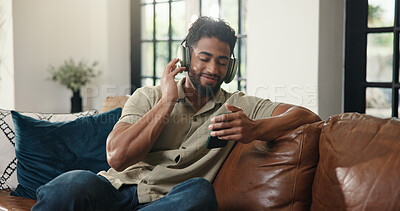 Buy stock photo Headphones, cellphone and man on sofa in home listening to music, playlist or radio in living room. Happy, audio tech and person streaming song, album or podcast on mobile app on weekend in house.
