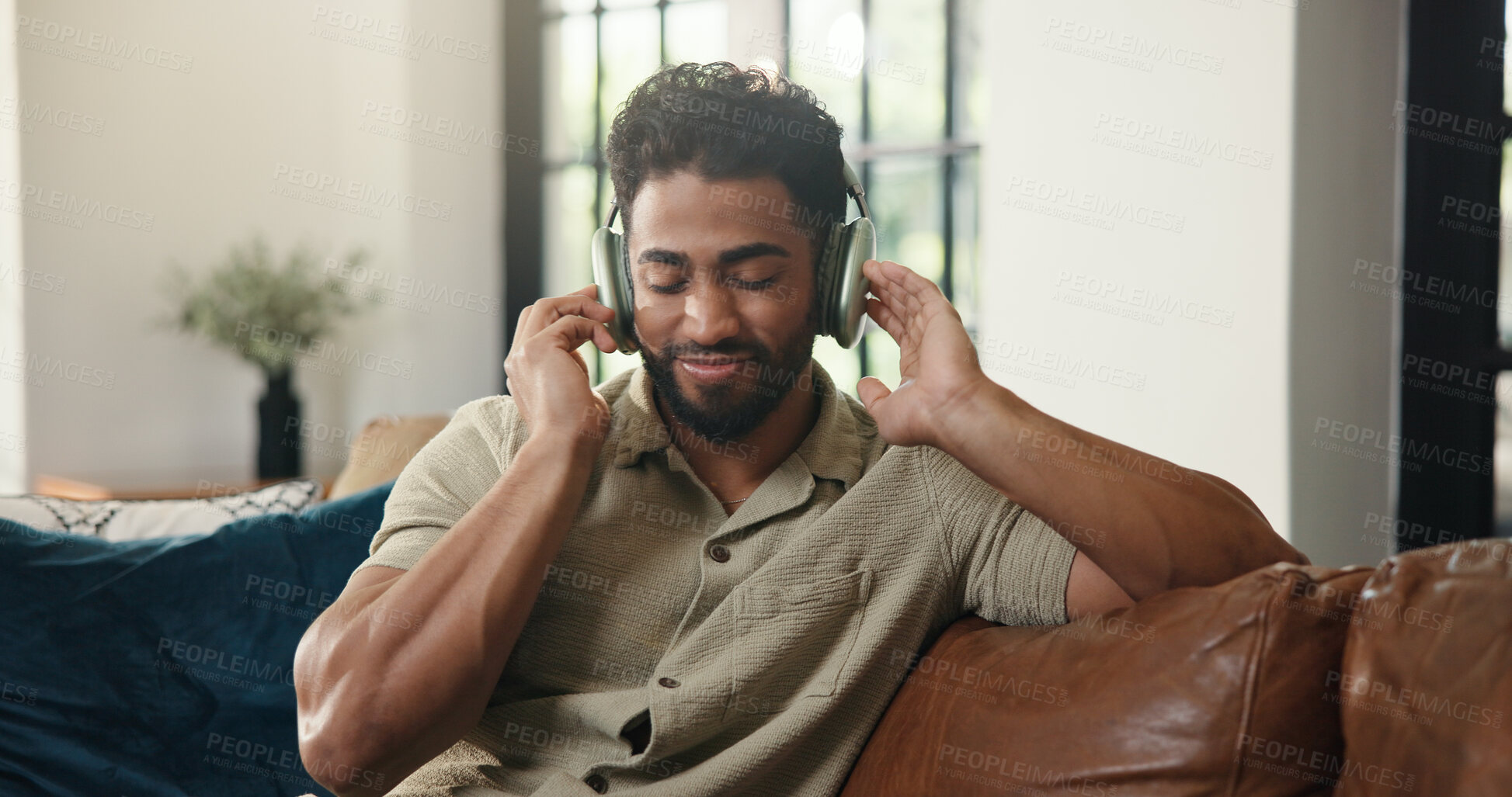 Buy stock photo Headphones, music and man on sofa in home listening to radio, playlist or song in living room. Happy, audio tech and male person streaming album for entertainment with chilling on weekend in house.