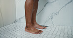 Man, legs and shower in bathroom with water for cleaning, hydration and dermatology in apartment. Person, feet and washing body with liquid for skincare hygiene, wellness and morning routine in home.