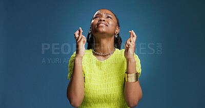 Buy stock photo Black woman, praying or fingers crossed with hope in studio for luck on a blue background. Female person, model or faith with desire, expectation or dream for chance, wish or miracle on mockup space