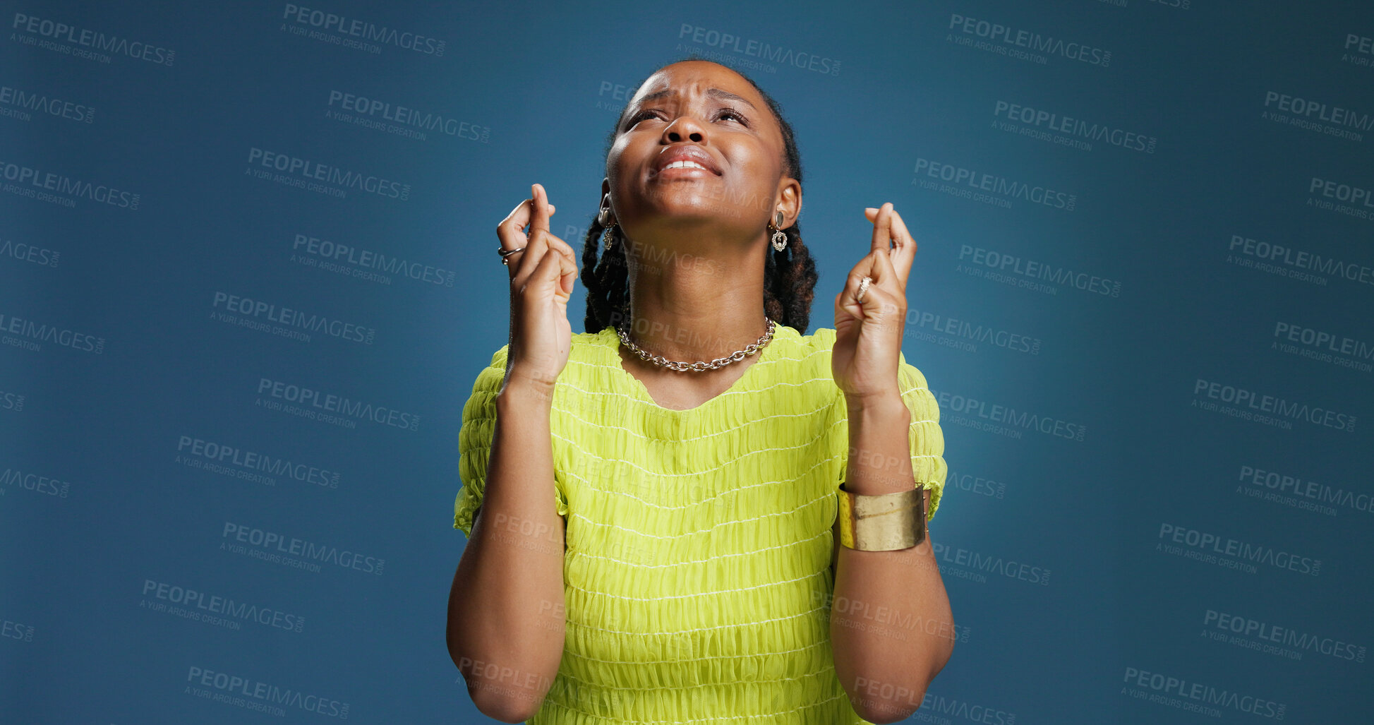 Buy stock photo Black woman, praying or fingers crossed with hope in studio for luck on a blue background. Female person, model or faith with desire, expectation or dream for chance, wish or miracle on mockup space