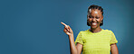 Portrait, pointing and black woman with smile in studio, show announcement or advertising with confidence. Banner, mockup space and person with hand gesture for promotion, happy or blue background