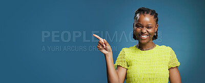 Buy stock photo Portrait, pointing and black woman with smile in studio, show announcement or advertising with confidence. Banner, mockup space and person with hand gesture for promotion, happy or blue background
