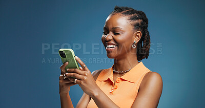 Buy stock photo Typing, smartphone and black woman in studio, laughing and communication on blue background. Mockup space, online joke and African person with cellphone, funny and message to contact, app and email