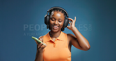 Buy stock photo Headphones, dance and black woman in studio with phone, listening and music playlist. Streaming, audio tech and African female person with space for album, radio or song for rhythm on blue background