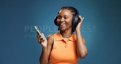 Buy stock photo Headphones, smile and black woman in studio with phone, music and playlist. Listening, audio tech and African female person with space for album, radio or song for rhythm or groove on blue background