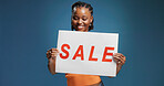 Happy, black woman or sign with sale for advertising or marketing on a blue studio background. Female person, promoter or model with poster, billboard or text for shopping deal, discount or low price