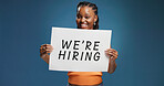 We are hiring, portrait or black woman in studio with poster, position or job available in onboarding. Recruitment, space or hr on blue background with paper, offer or candidate in career opportunity