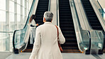 Woman, escalator and airport for travel with bag, luggage and walk for global departure. Mature person, business trip and  at stairs, immigration or international flight at terminal for corporate job